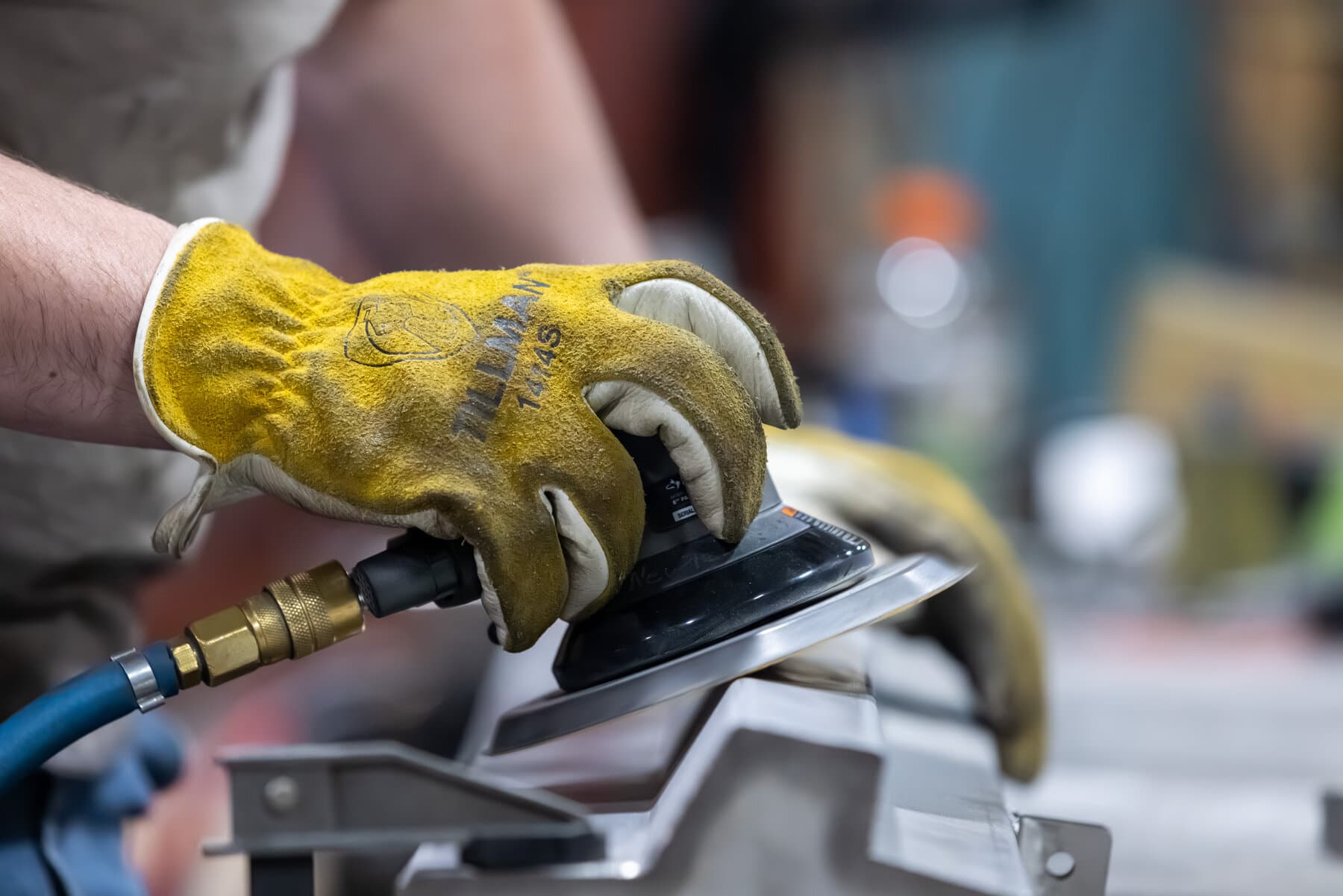 New Tech Metals technician dual-action sanding a stainless part