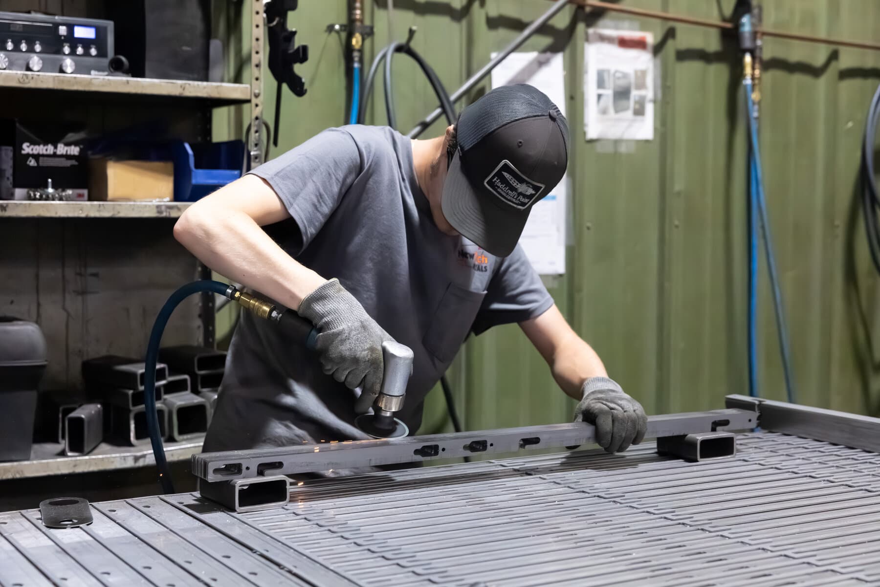 Operator manually deburring a welded frame with a die grinder