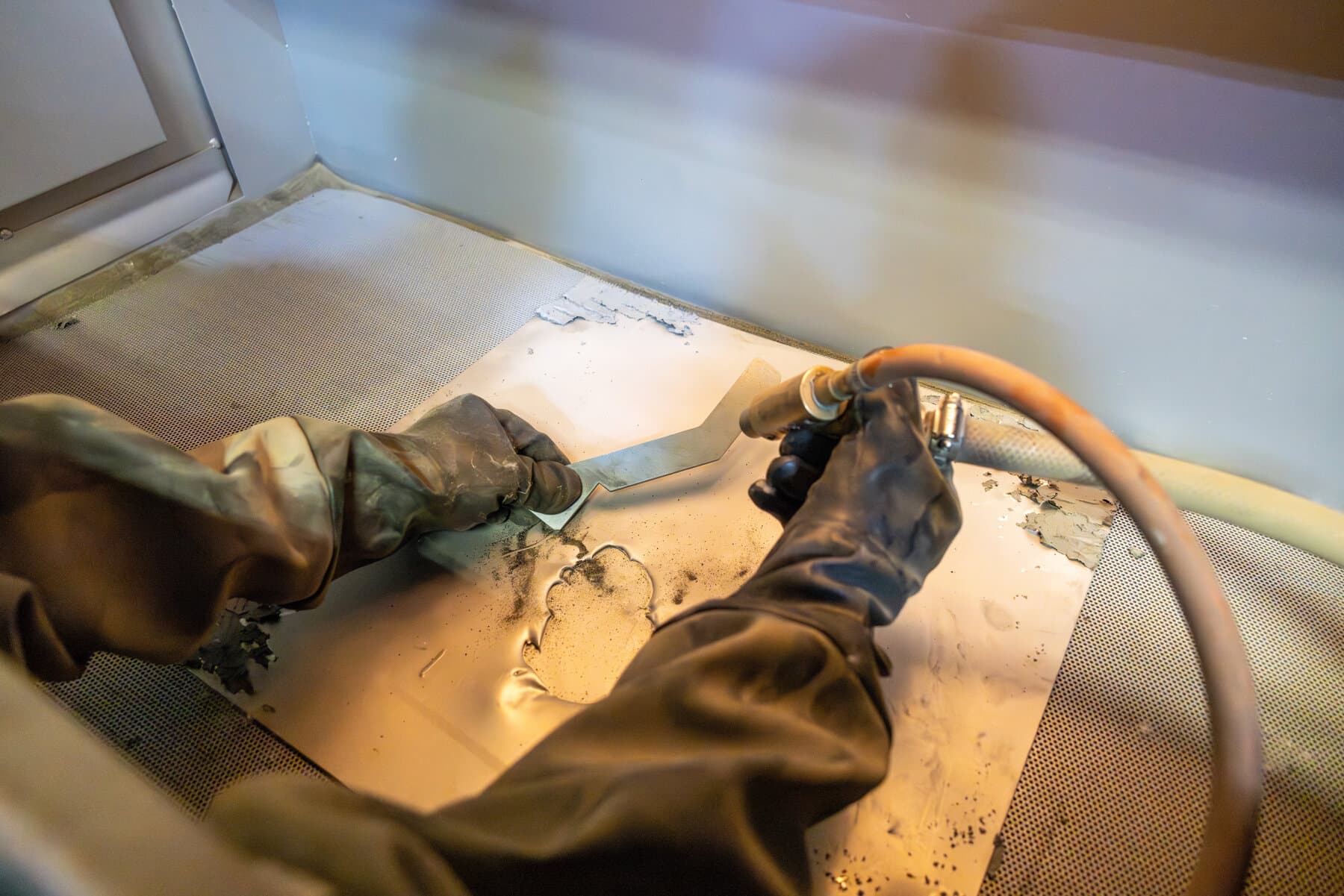 Sandblasting a metal part inside a blast cabinet