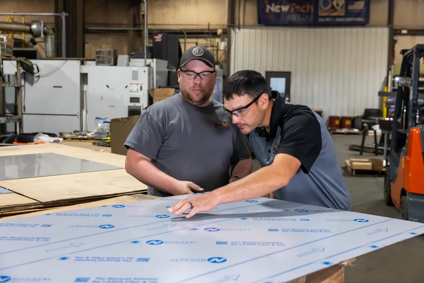 New Tech Metals engineer and operator reviewing a laser-ready sheet on the shop floor