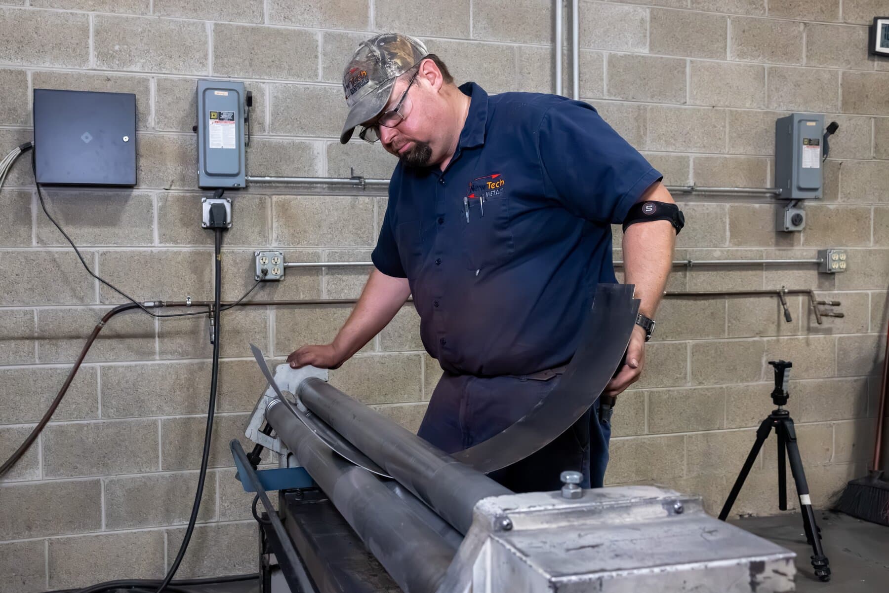New Tech Metals technician rolling a curved metal panel
