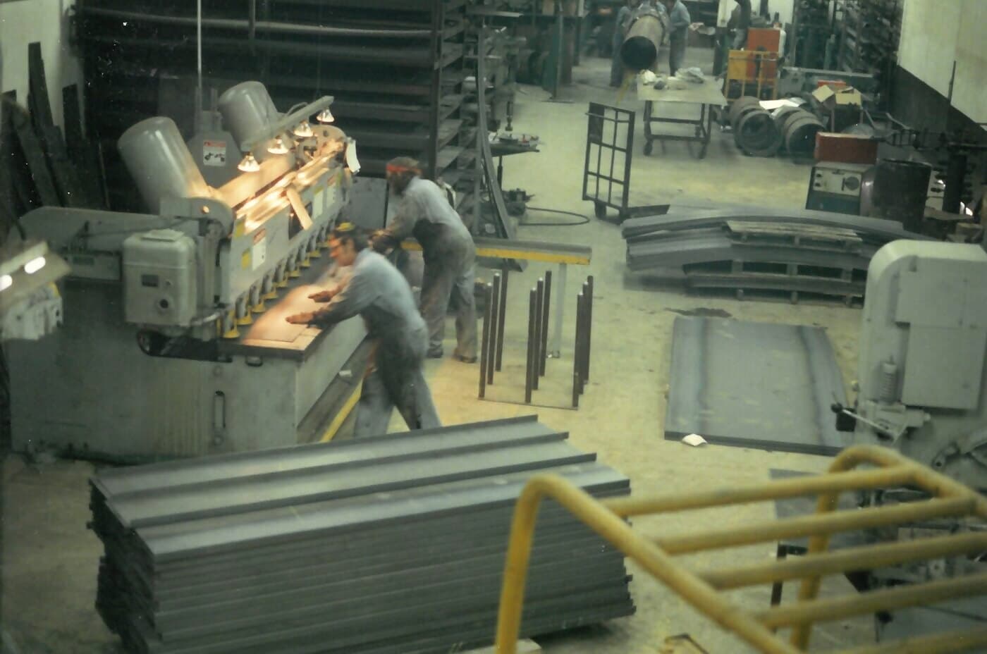 New Tech Metals shop floor in the 1980s, fabricators running a shear and forming line on the original production floor
