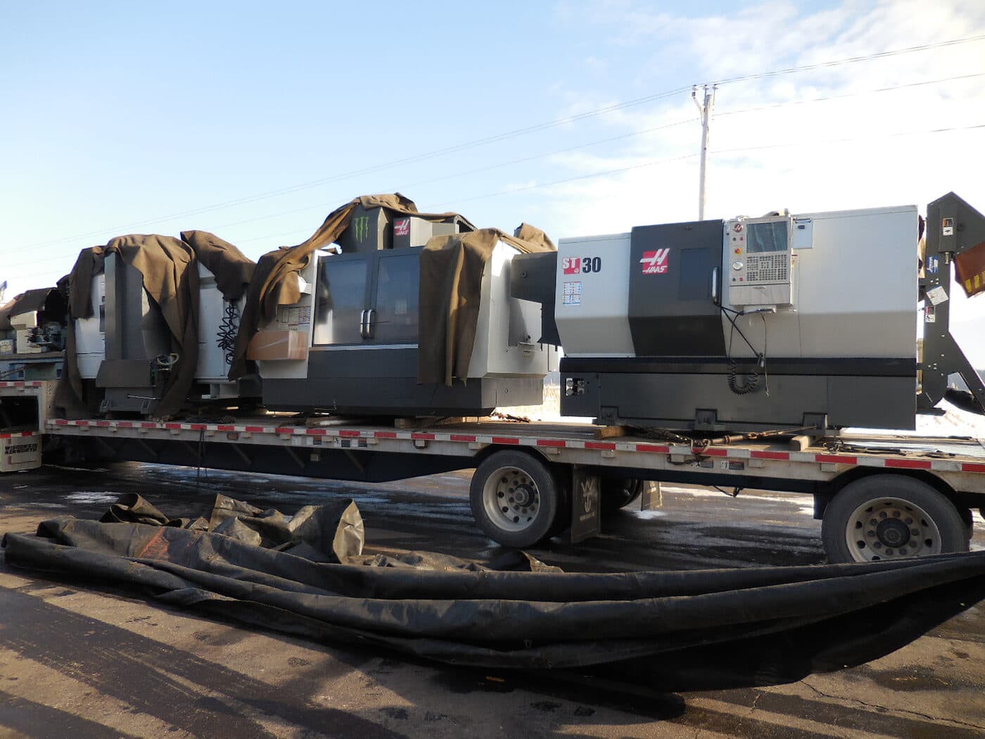 HAAS CNC machines arriving by flatbed when New Tech Metals acquired a local CNC machine shop in 2015