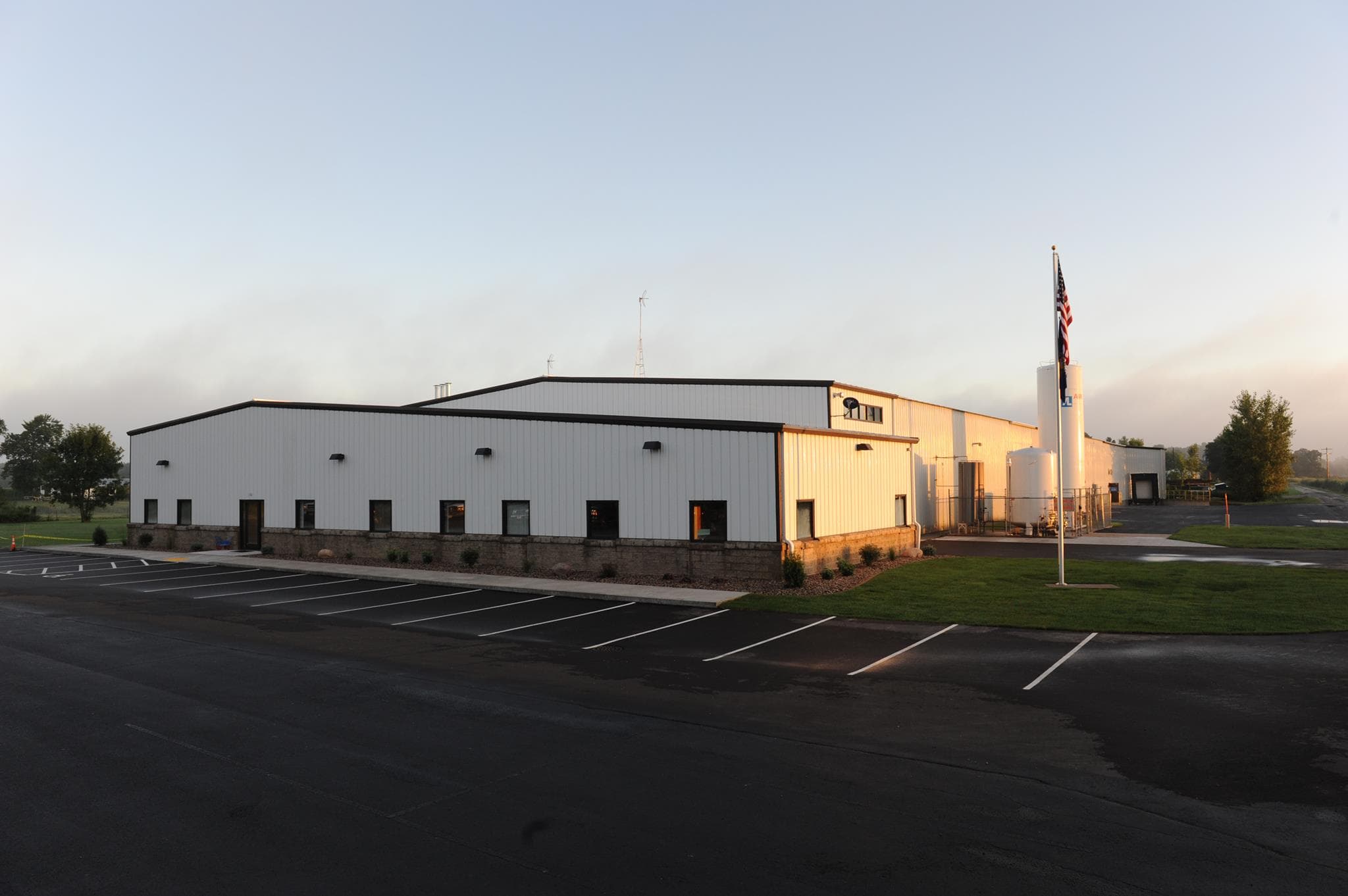 New Tech Metals facility, exterior of the New Franken, Wisconsin building at sunrise with an American flag flying out front