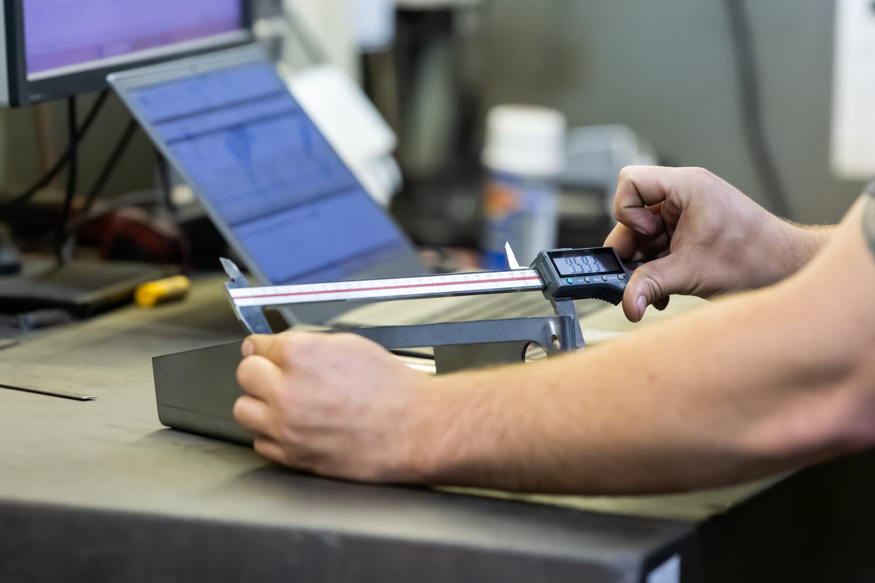 Close-up of a machined steel part being measured with a digital caliper