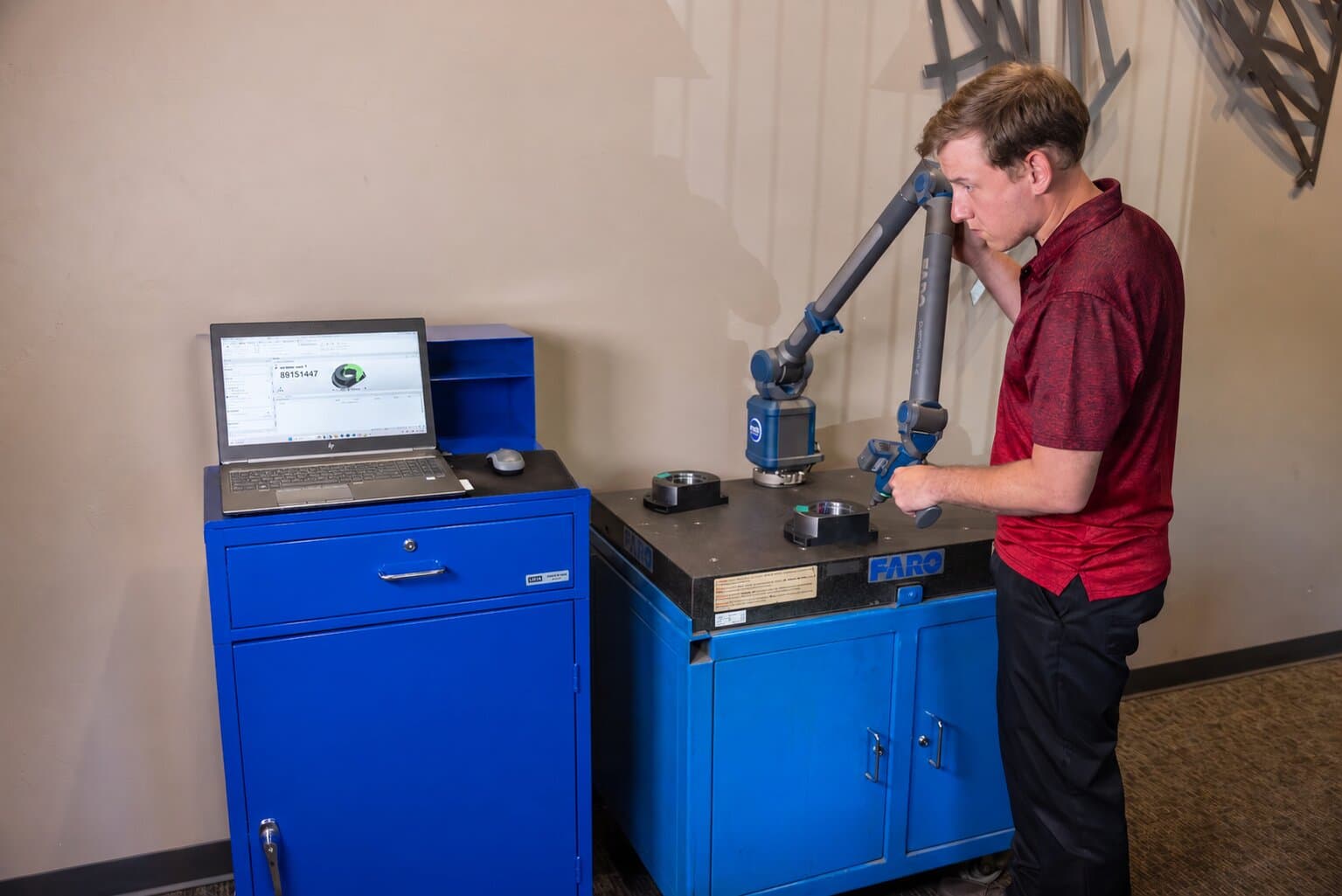 New Tech Metals quality technician running a FARO Quantum coordinate measuring machine arm to inspect a machined part
