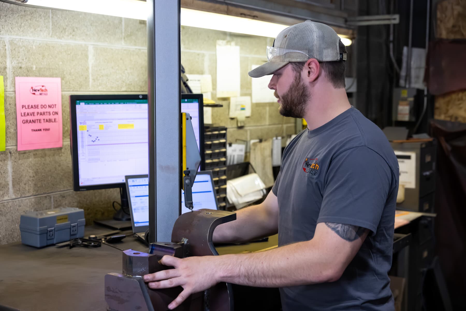 Operator running a digital height gauge at a granite inspection station