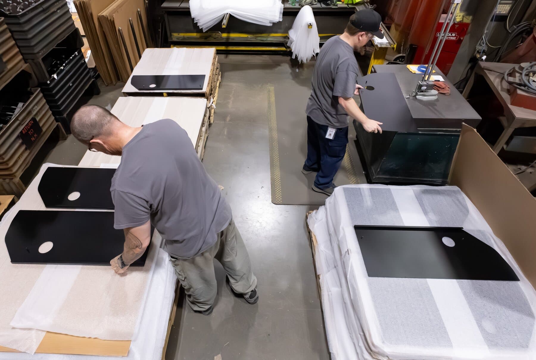 Two New Tech Metals technicians inspecting finished black powder-coated panels in process
