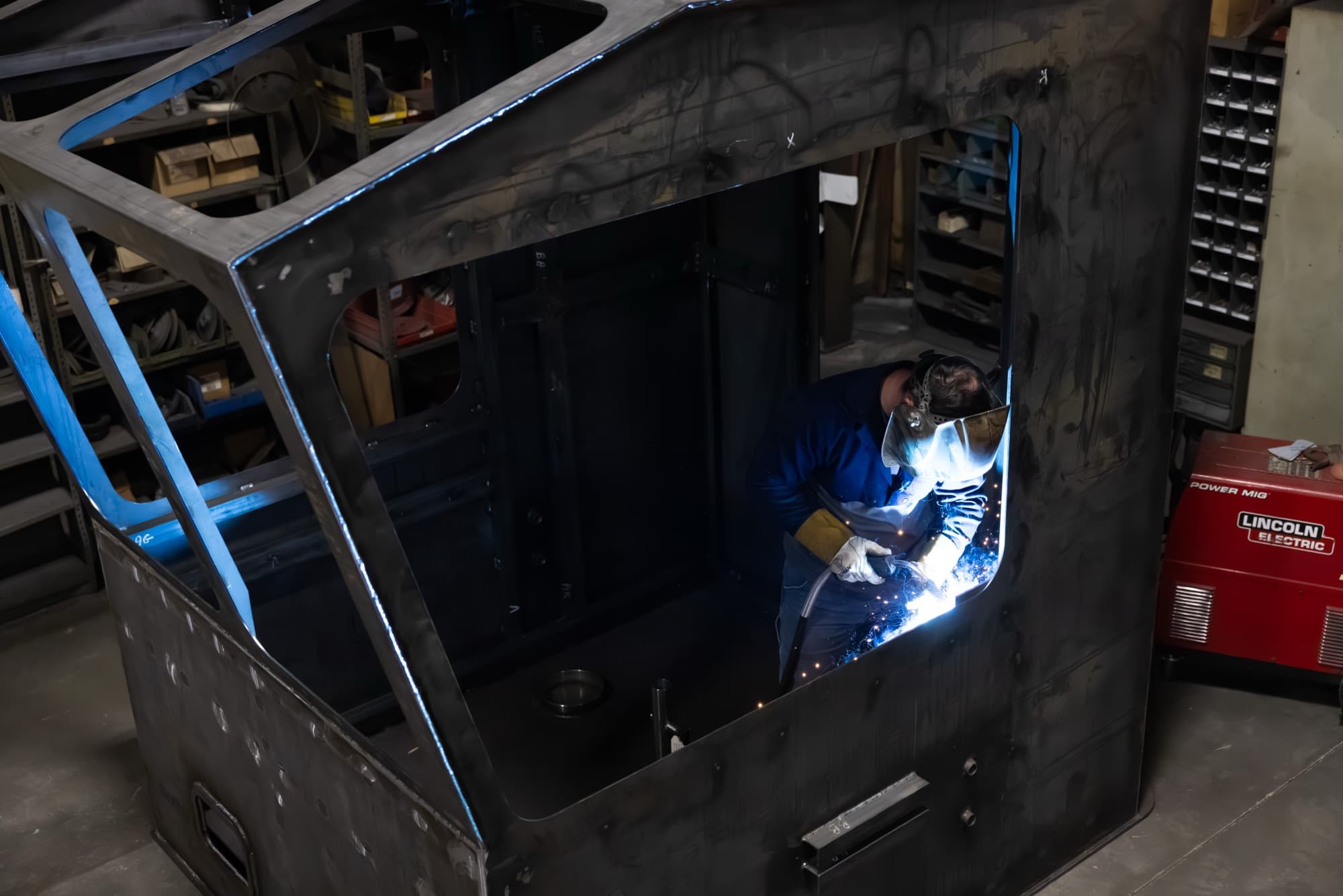 New Tech Metals welder fabricating a large steel cab enclosure in the shop