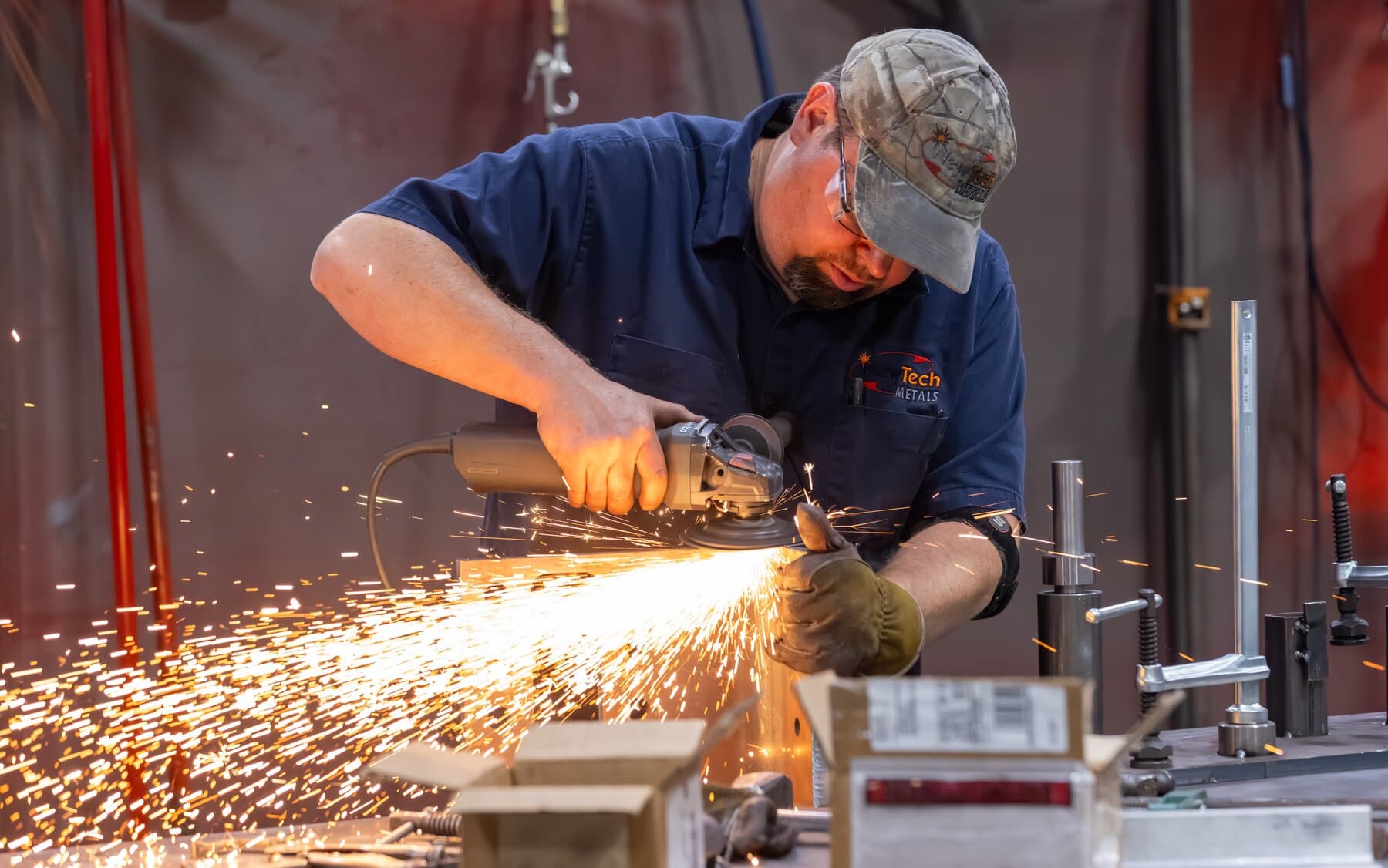 New Tech Metals welder grinding a weld with an angle grinder, sparks flying