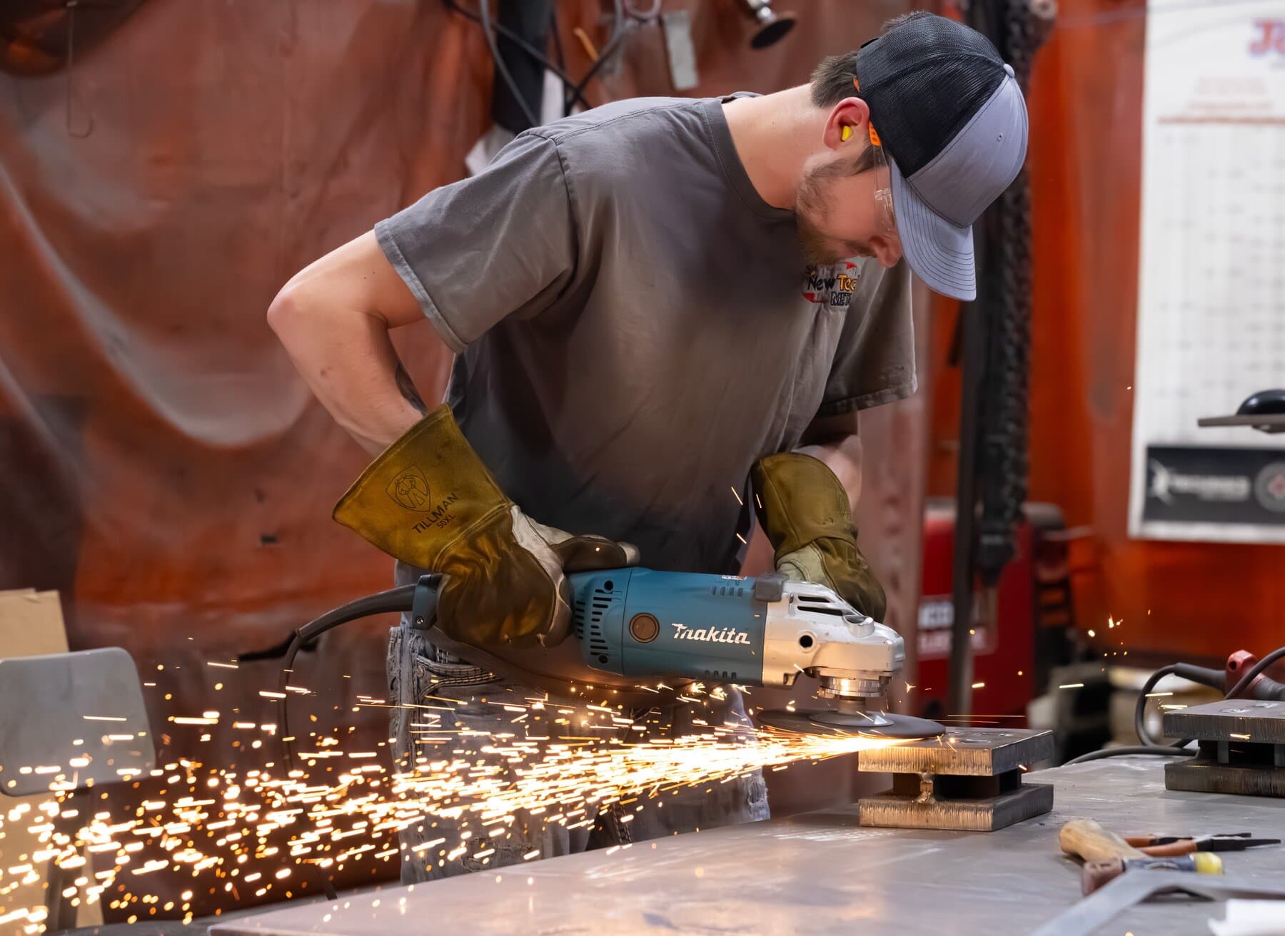 Welder grinding a part with sparks at the fabrication bench